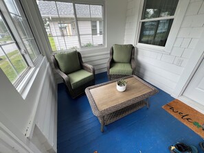 A room with two wicker chairs, a small table with a plant, and a blue floor.