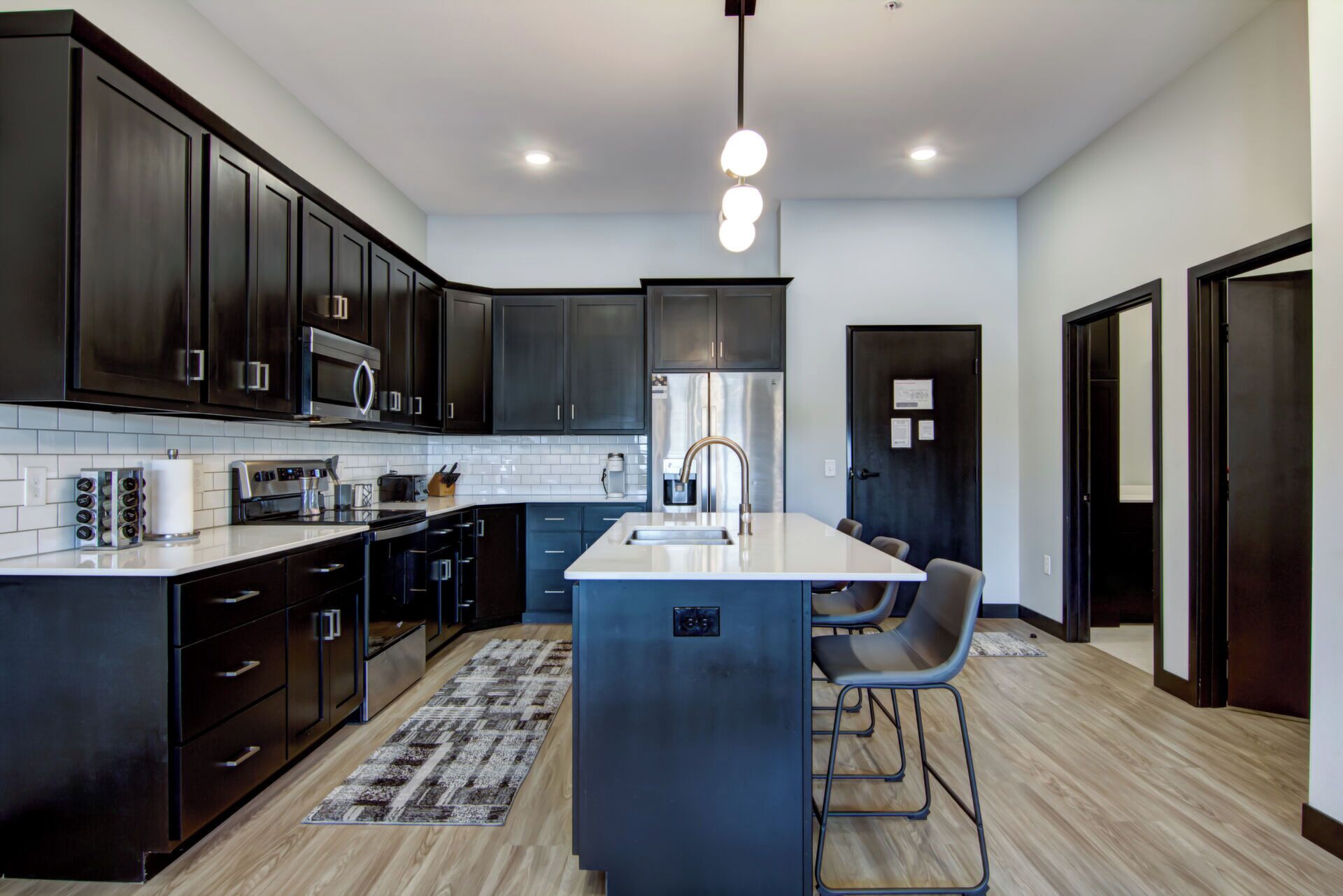 A modern kitchen with dark cabinetry, a central island, and a stainless steel refrigerator.