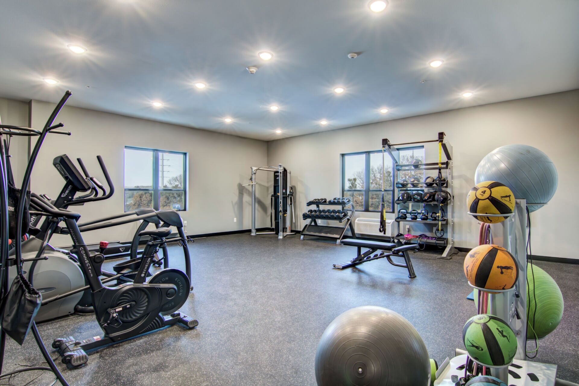 Uma academia com equipamentos de ginástica, um banco e bolas de exercício.