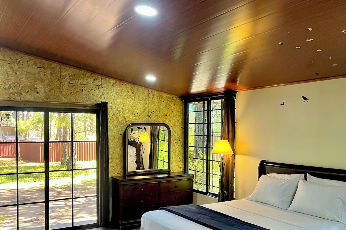 A bedroom with a large bed, a dresser, a mirror, and a window.