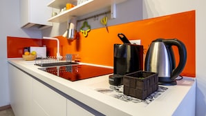 Une cuisine moderne avec un plan de travail blanc, une cuisinière encastrée et une bouilloire.