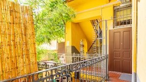 Un bâtiment jaune avec un escalier en métal et une porte marron.