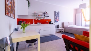 Une pièce moderne et bien éclairée, comprenant un coin cuisine, une table à manger avec des chaises, un canapé et un lit.