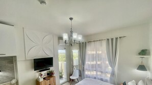 Un dormitorio con cama, televisor, escritorio y silla.