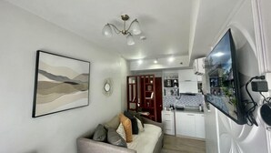 Un espacio habitable compacto con sofá, zona de comedor y kitchenette.