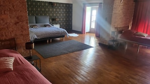 Una camera da letto con pavimento in legno, un letto con copriletto decorato, un comodino con una lampada e un'ampia finestra con tende.