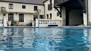 Una piscina con un edificio in pietra sullo sfondo.