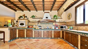 A spacious kitchen with wooden cabinets, a tiled floor, and a large window.