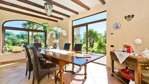 A dining area with a wooden table, chairs, and a view of greenery outside.