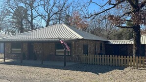 Ein rustikales Steinhaus mit Metalldach, Holzzaun und einer amerikanischen Flagge.