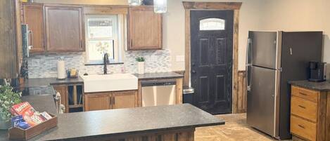 A kitchen with wooden cabinets, a central island, stainless steel appliances, and hanging light fixtures.