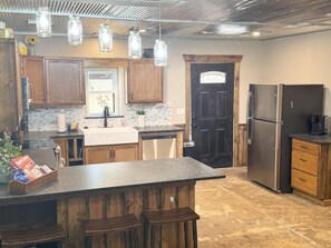Una cocina con armarios de madera, una isla central, electrodomésticos de acero inoxidable y lámparas colgantes.
