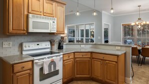 A kitchen with wooden cabinets, a white stove, and pendant lighting.