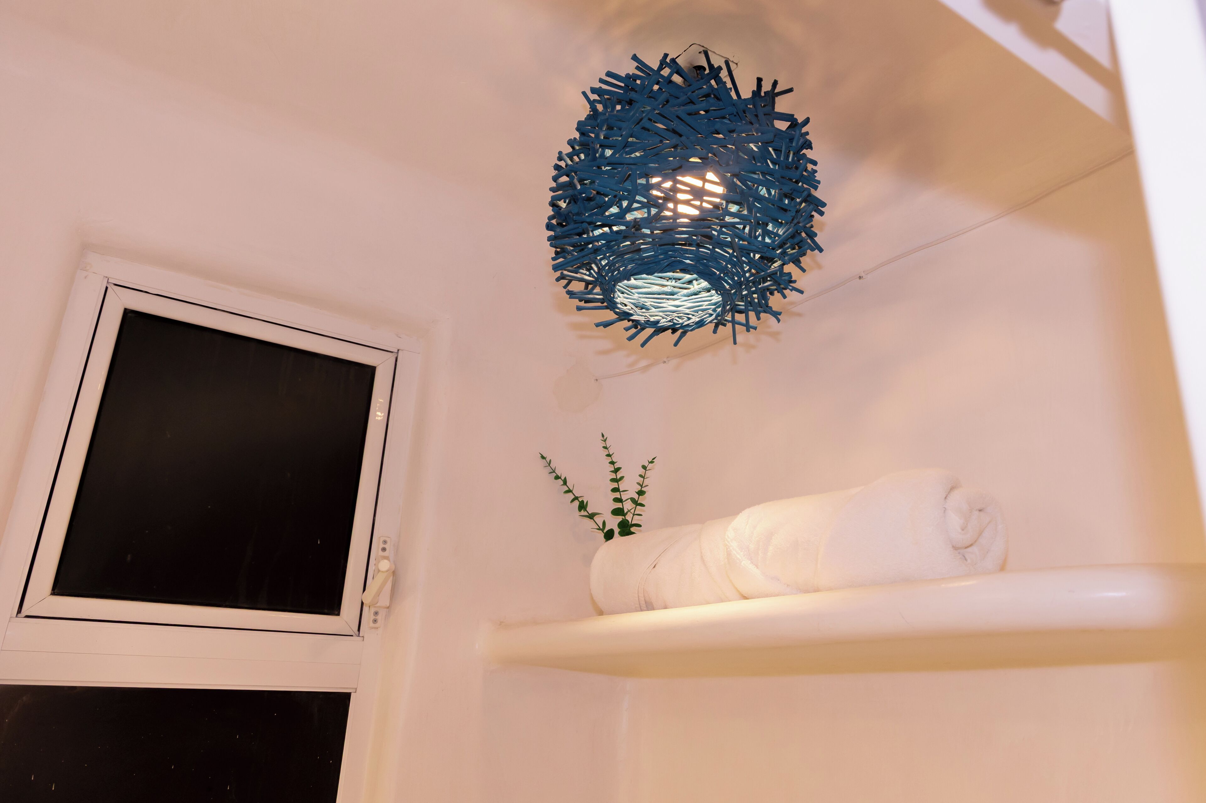 A bathroom with a white bathtub, a towel on the edge, and a blue decorative light fixture.