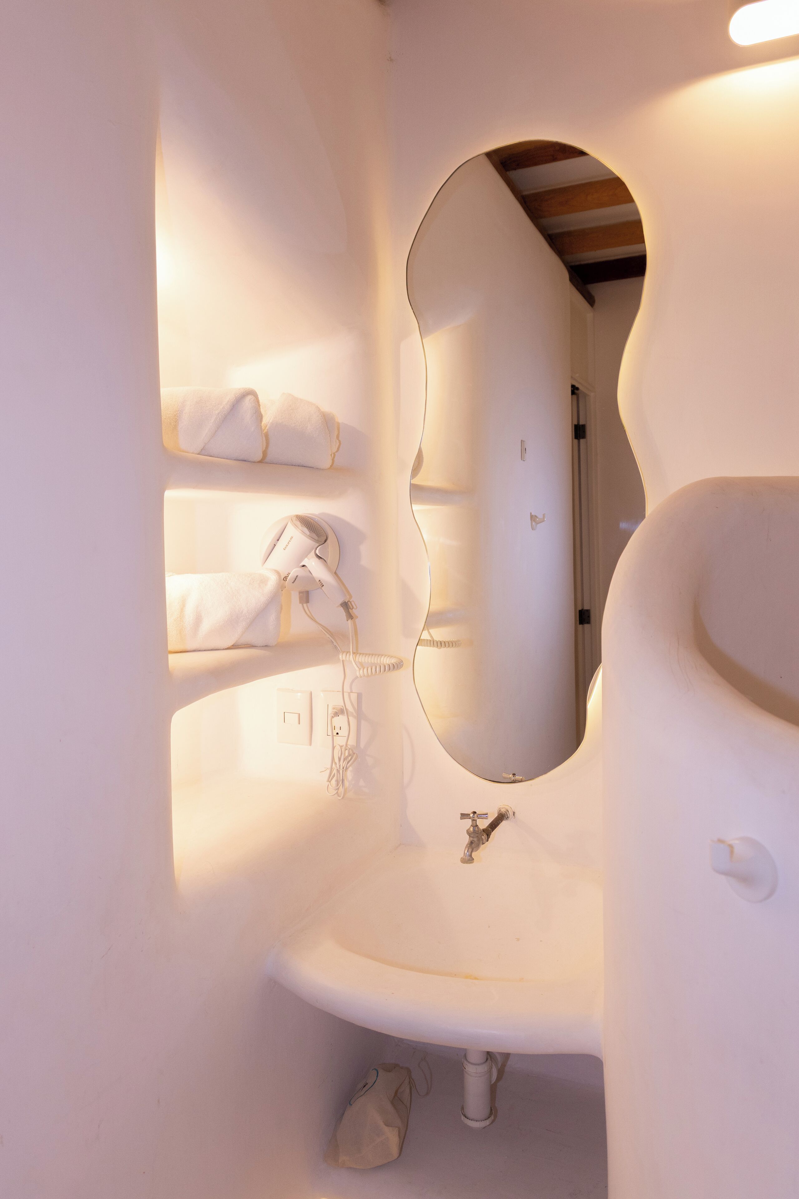 A bathroom with a white sink, a mirror, and a towel rack.