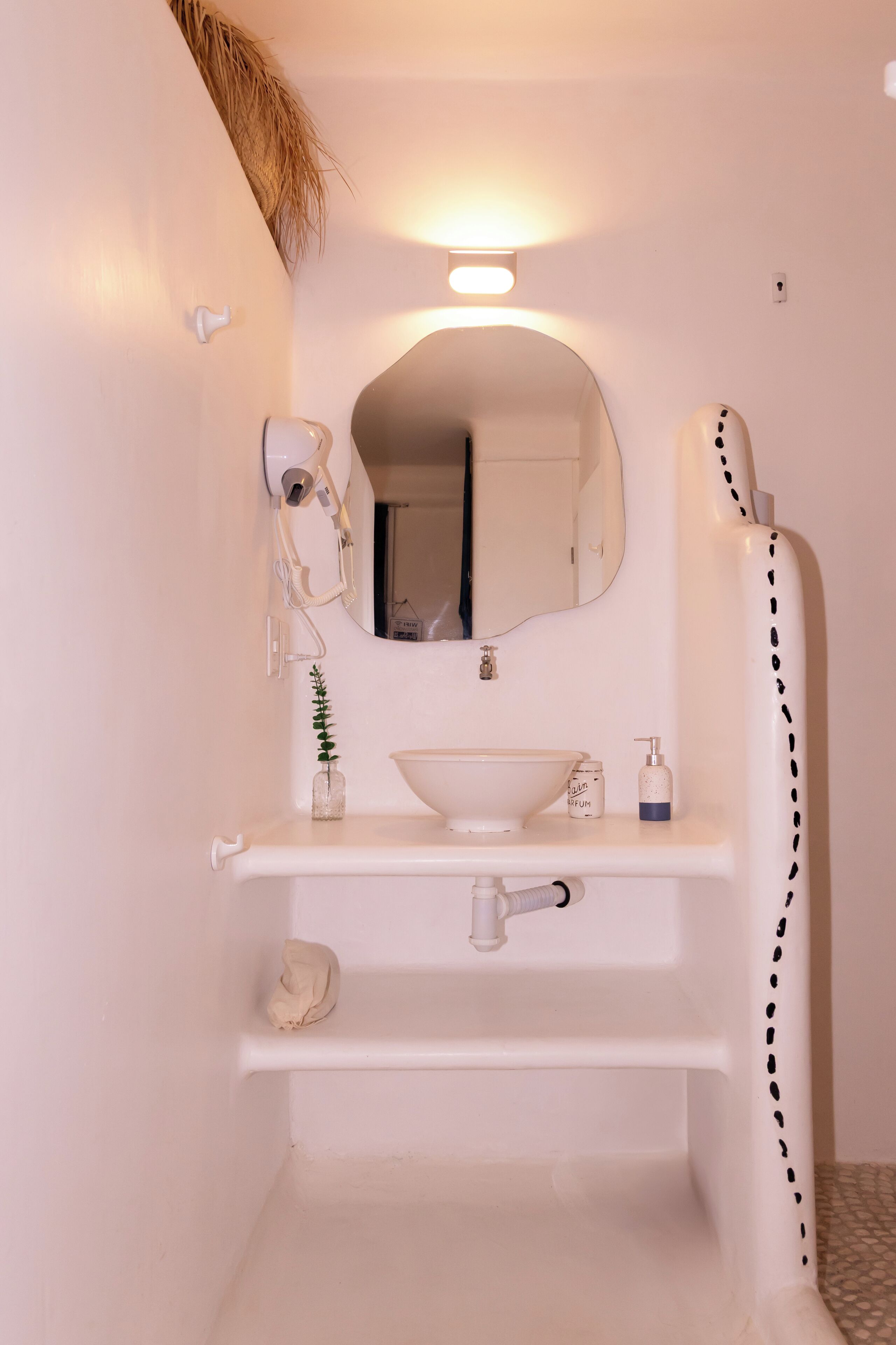A bathroom with a white sink, mirror, and shower.