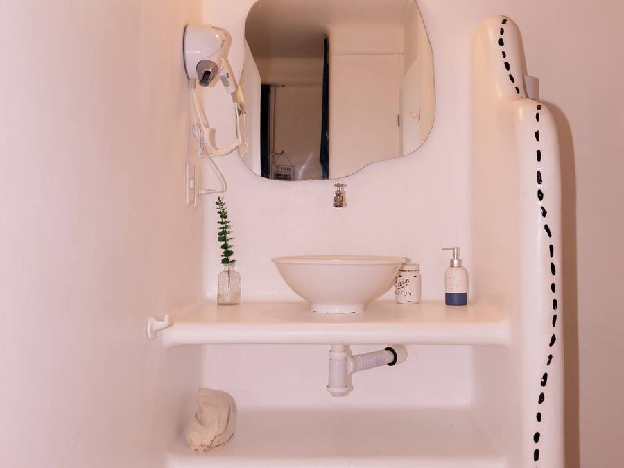 A bathroom with a white sink, mirror, and shower.