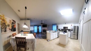 A spacious kitchen with white cabinets, a central island, and a dining area with a table and chairs.