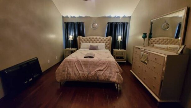 A bedroom with a bed, nightstands, a dresser, a ceiling fan, and a mirror.