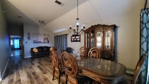 A dining area with a wooden table and chairs, a chandelier, and a wooden cabinet.