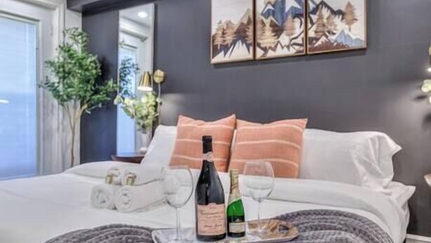 Een net opgemaakt bed met een fles champagne, glazen en een schaal lekkernijen.