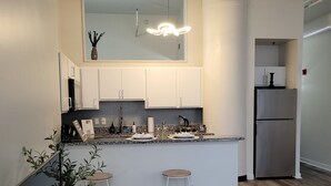 Una cocina moderna con armarios blancos, un refrigerador de acero inoxidable y una encimera de mármol.