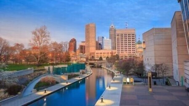 Un paisaje urbano con un río, edificios modernos y una zona de parque.