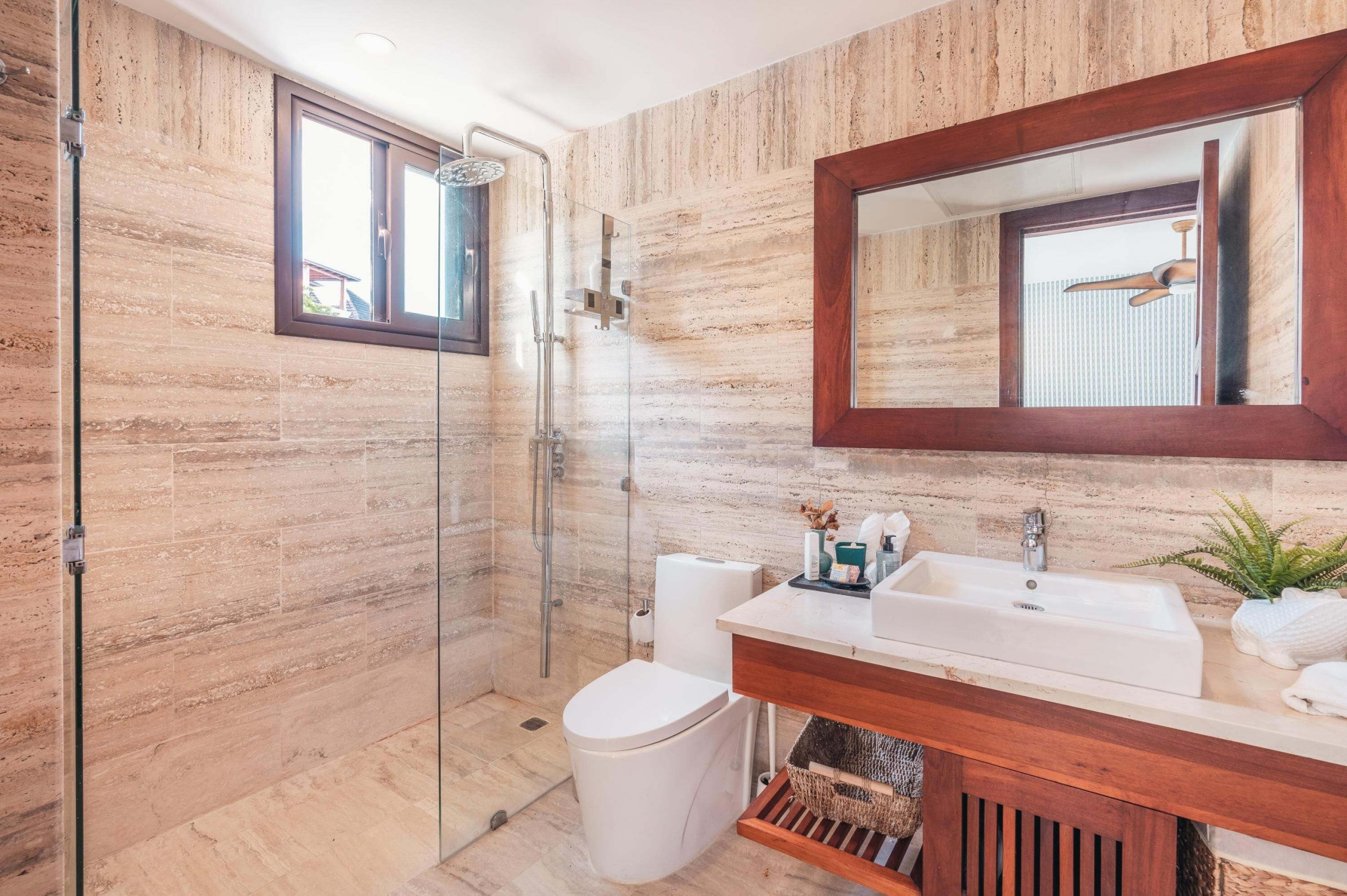 A modern bathroom with a glass-enclosed shower, a large mirror, and a wooden vanity with a sink.