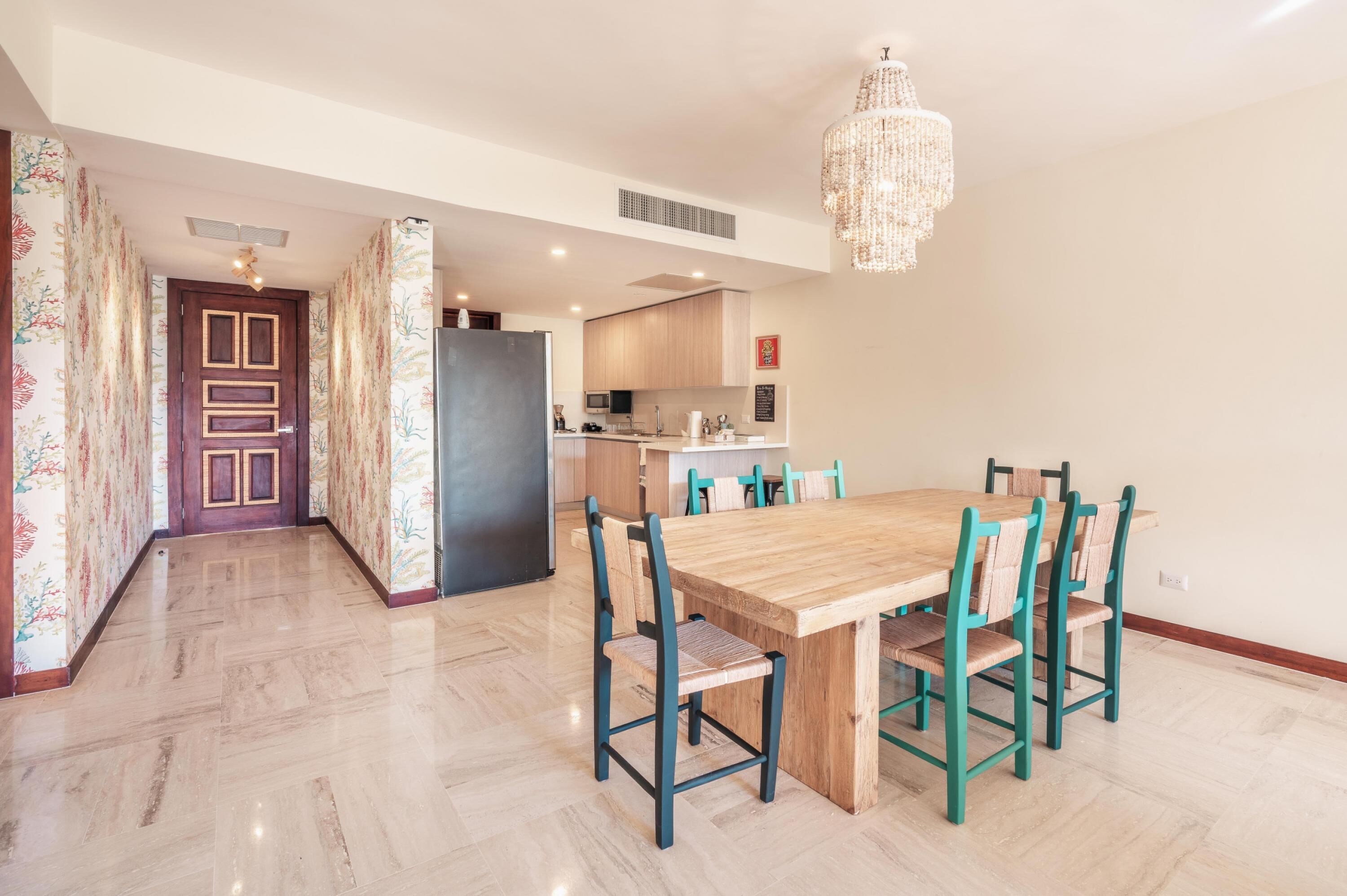 Una cucina moderna con isola centrale, zona pranzo con tavolo e sedie in legno e lampadario.