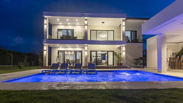 A modern two-story house with a swimming pool, outdoor seating, and a well-lit patio area. - Brand new luxury villa located in a the most pristine gated community SOV
 (Sosúa)