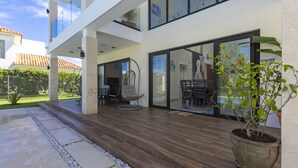 A modern outdoor patio with a wooden deck, seating area, and a potted plant. - Brand new luxury villa located in a the most pristine gated community SOV
 (Sosúa)