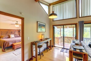 Une chambre avec un lit, un bureau avec deux tabourets et un balcon avec vue.