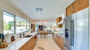 A modern kitchen with a large stainless steel refrigerator, wooden cabinets, and a large window providing natural light. - 2 Mi to Downtown: Luxe Palm Springs Home! (Palm Springs)