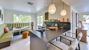 A modern kitchen with a central island, seating area, and large windows. - 2 Mi to Downtown: Luxe Palm Springs Home! (Palm Springs)
