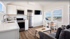 Een moderne keuken met witte kasten, roestvrijstalen apparatuur en een eethoek met een tafel en stoelen.