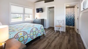 Een slaapkamer met een bed, een televisie, een stoel, een kledingkast en een raam.