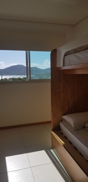Une chambre avec un lit superposé, une grande fenêtre et une vue sur une montagne et le paysage urbain.