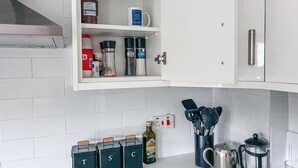 Cocina con armarios blancos, un especiero y una cafetera.