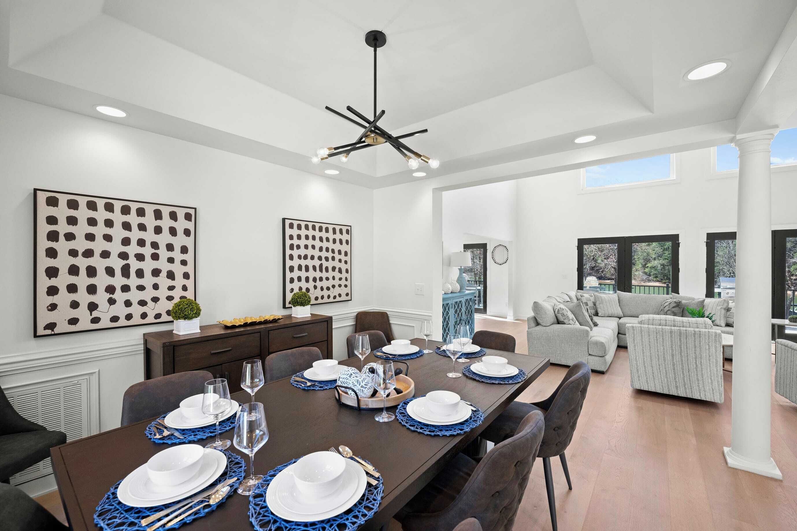 Uma sala de jantar moderna com uma mesa comprida posta para seis pessoas, rodeada por assentos confortáveis.