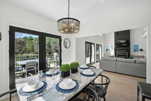 A dining area with a marble table set for four, a chandelier, and a view of the outdoors. - Knotty Pines by Avantstay Lake Views, Renovated (Sherrills Ford)