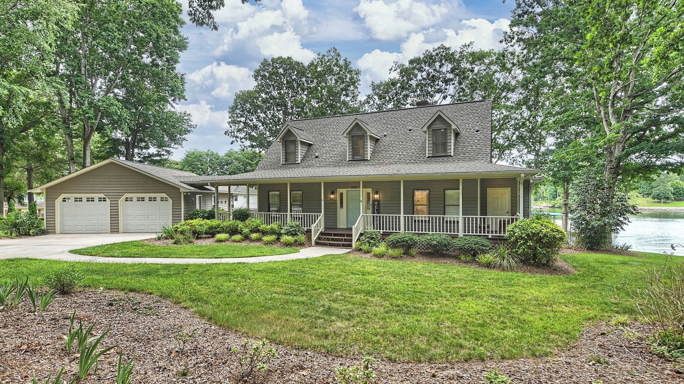 A two-story house with a front porch, garage, and a well-maintained lawn.