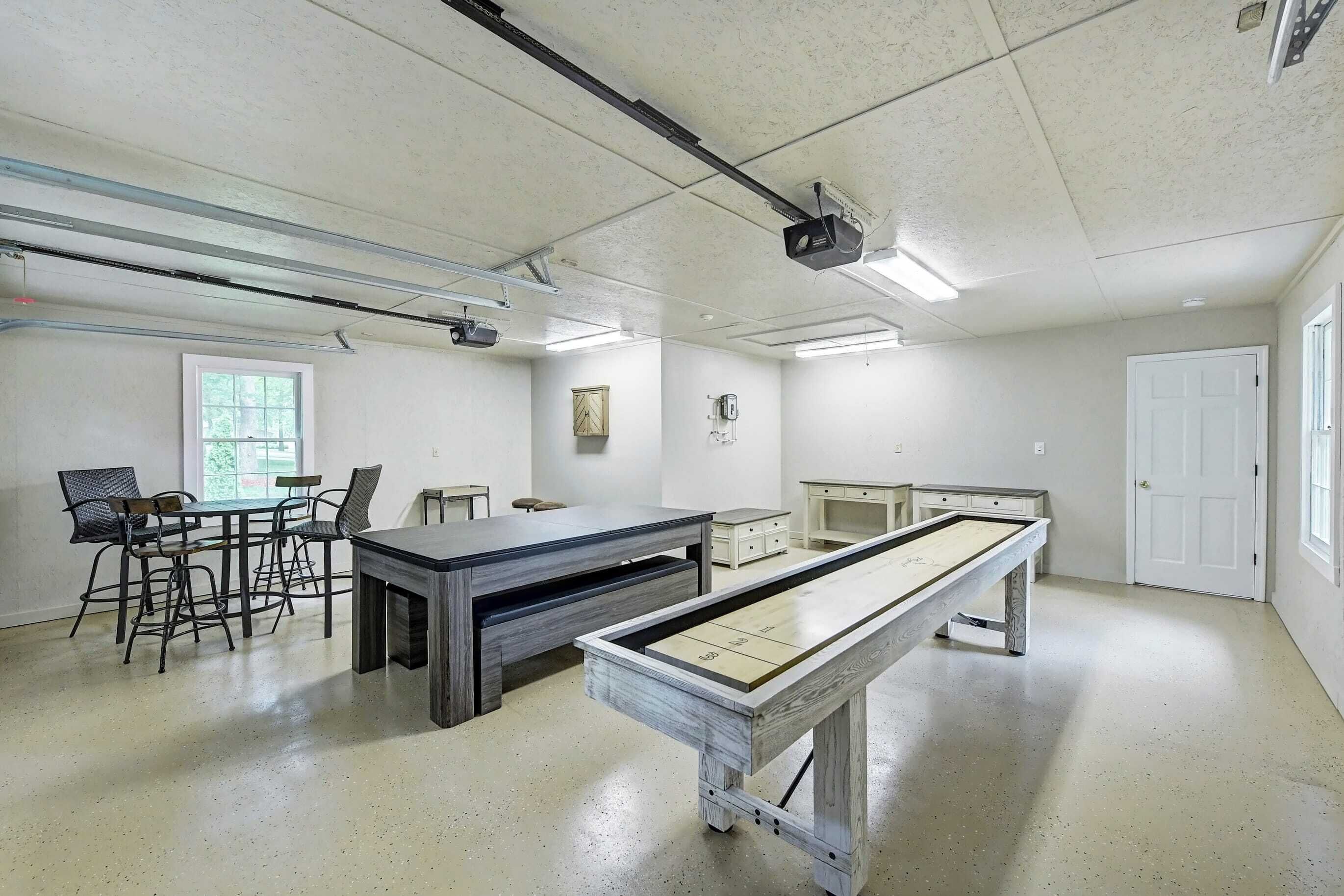 Une pièce équipée d’une table de billard, de tabourets de bar, d’une petite table et d’un projecteur fixé au plafond.