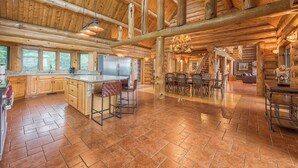 A spacious log cabin with a large kitchen area featuring a central island, bar stools, and a dining area with a chandelier. - Azalea Retreat- The Lodge by Avantstay Best View (Sherrills Ford)