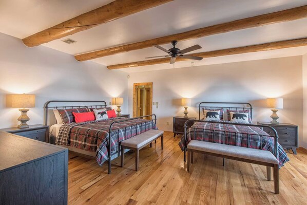 Une chambre avec deux lits, des poutres en bois, un ventilateur de plafond et des lampes de chevet.