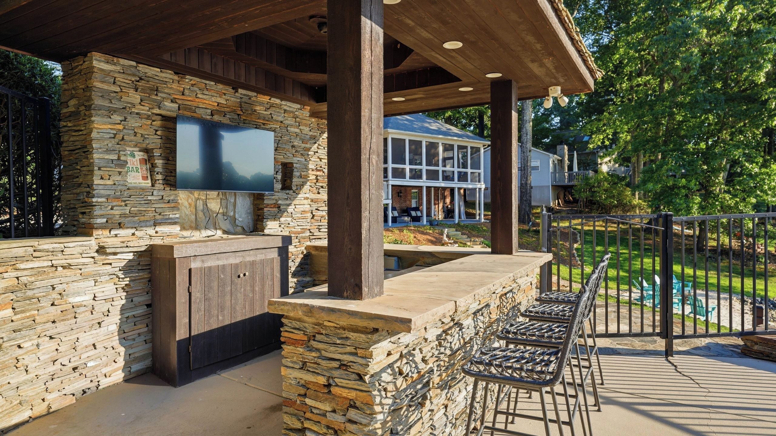 An outdoor patio with stone walls, a flat-screen TV, and outdoor seating.