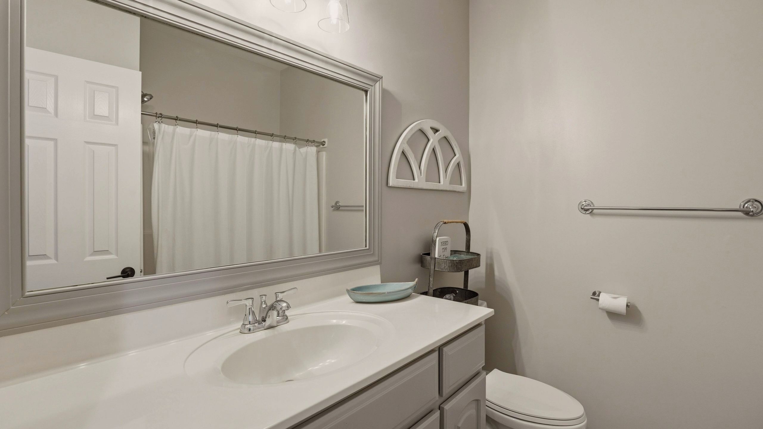 A bathroom with a white sink, a large mirror, a towel rack, and a toilet.
