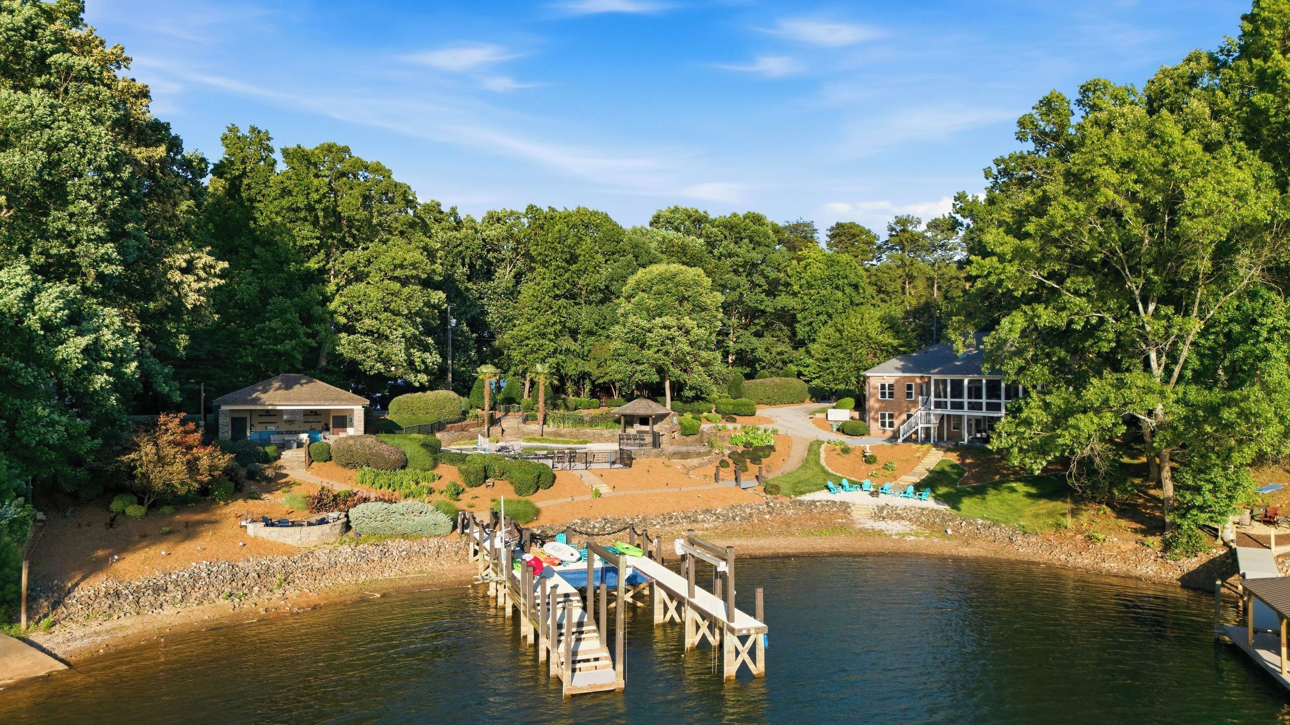 A lakeside property with a dock, a gazebo, and a house with a large deck.