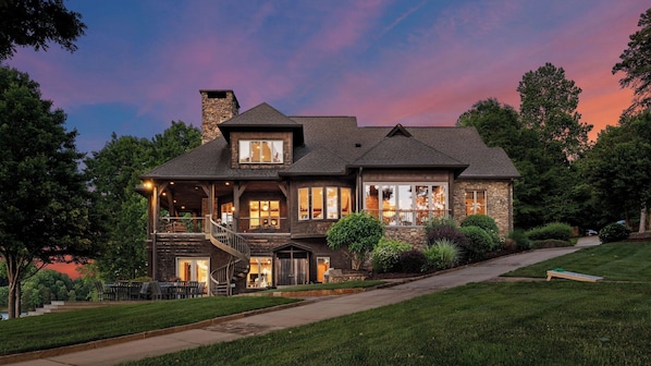 A two-story house with a stone facade, large windows, and a covered porch.