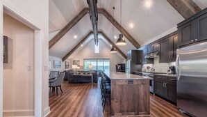 A spacious kitchen with a central island, dark wooden cabinets, and a stainless steel refrigerator. - Azalea Retreat by Avantstay Sleeps 34 & Pool (Sherrills Ford)
