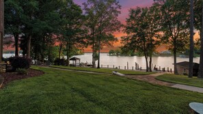 A lakeside view with a gazebo, dock, and grassy area.